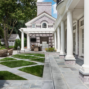 Foto di un ampio patio o portico classico dietro casa con piastrelle e una pergola