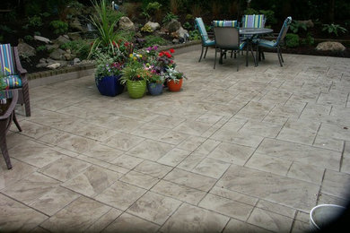 Example of a mid-sized transitional backyard stamped concrete patio design in Portland with no cover