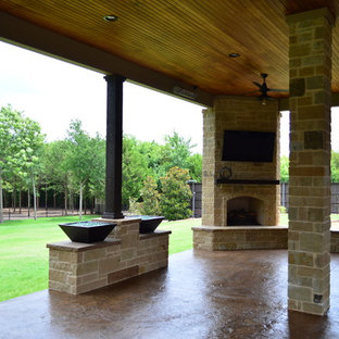Ispirazione per un ampio patio o portico boho chic dietro casa con un caminetto, cemento stampato e un tetto a sbalzo