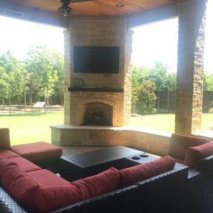 Immagine di un ampio patio o portico eclettico dietro casa con un caminetto, cemento stampato e un tetto a sbalzo