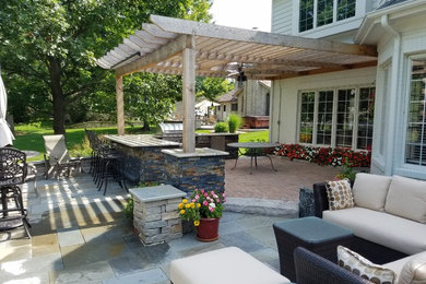 Imagen de patio clásico renovado de tamaño medio en patio trasero con cocina exterior, adoquines de hormigón y pérgola