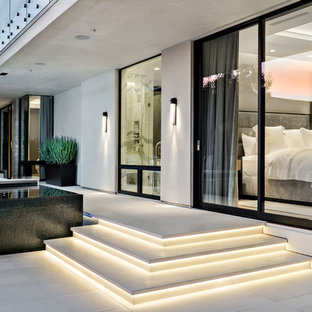 Idee per un patio o portico design di medie dimensioni e dietro casa con piastrelle e un tetto a sbalzo