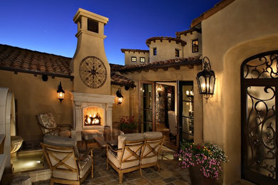 Large tuscan courtyard stone patio photo in Phoenix with no cover and a fireplace
