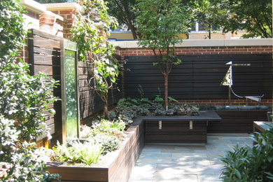 Imagen de patio contemporáneo pequeño sin cubierta en patio trasero con fuente y adoquines de piedra natural