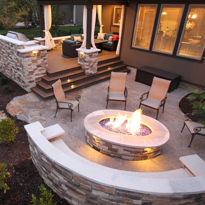 Example of a large trendy backyard stamped concrete patio design in Kansas City with a fire pit and a roof extension
