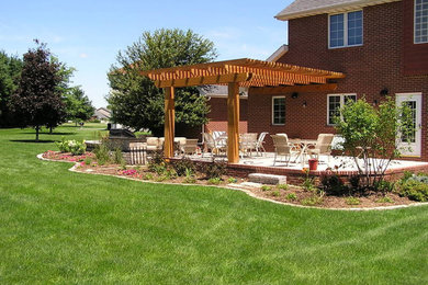 Immagine di un grande patio o portico classico dietro casa con una pergola e pavimentazioni in mattoni