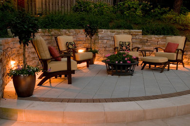 This is an example of a medium sized classic back patio in New York with a fire feature, concrete paving and no cover.