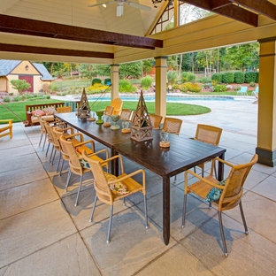 Idee per un grande patio o portico chic dietro casa con un focolare, cemento stampato e un tetto a sbalzo