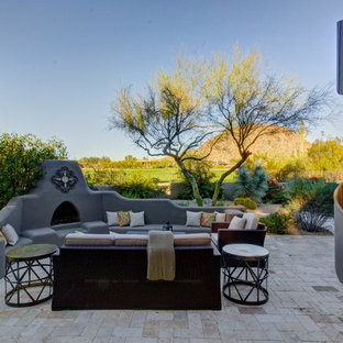 Foto di un ampio patio o portico american style dietro casa con pavimentazioni in pietra naturale, nessuna copertura e un caminetto