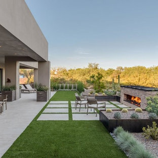 Ispirazione per un grande patio o portico minimalista dietro casa con un focolare, lastre di cemento e un tetto a sbalzo