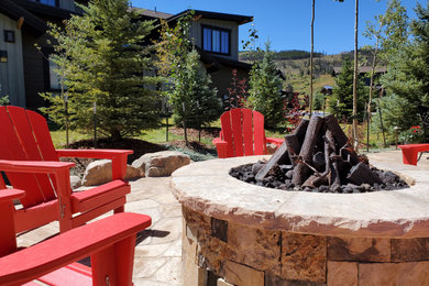 Mountain style side yard stone patio photo in Other with a fire pit