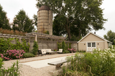 Inspiration för mellanstora lantliga uteplatser längs med huset, med grus och en pergola