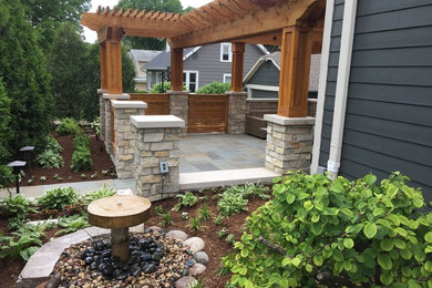 Mid-sized arts and crafts backyard stone patio fountain photo in Chicago with a pergola