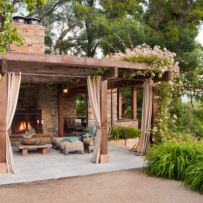 Example of a mid-sized tuscan backyard stone patio design in San Francisco with a pergola and a fireplace