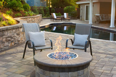 Example of a large minimalist backyard concrete paver patio design in Orange County with a fire pit and a pergola
