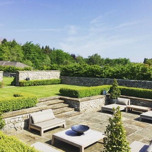Ispirazione per un ampio patio o portico chic dietro casa con pavimentazioni in pietra naturale e nessuna copertura