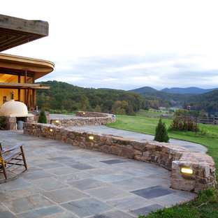 Esempio di un patio o portico stile rurale dietro casa con nessuna copertura, un focolare e pavimentazioni in pietra naturale