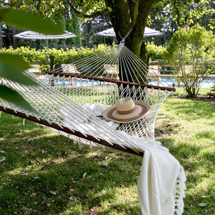 Idee per un ampio patio o portico costiero dietro casa con un giardino in vaso, pavimentazioni in pietra naturale e un tetto a sbalzo