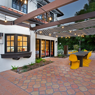 Immagine di un patio o portico boho chic di medie dimensioni e nel cortile laterale con piastrelle e un parasole