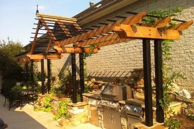 Eclectic courtyard concrete patio kitchen photo in Austin with a pergola