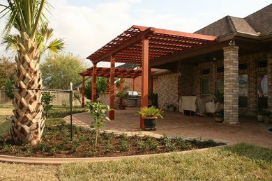 Example of a backyard concrete paver patio design in Austin with a pergola
