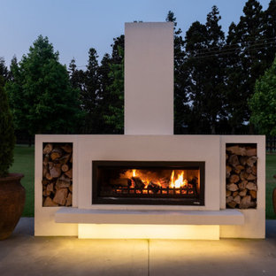 Idee per un patio o portico minimalista di medie dimensioni e davanti casa con un caminetto, lastre di cemento e un tetto a sbalzo
