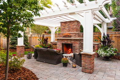Ejemplo de patio clásico de tamaño medio en patio trasero con brasero, adoquines de hormigón y pérgola