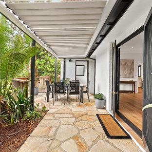 Inspiration for a mid-sized transitional backyard patio in Sydney with natural stone pavers and an awning.