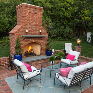 Foto di un grande patio o portico classico dietro casa con un focolare, pavimentazioni in mattoni e nessuna copertura