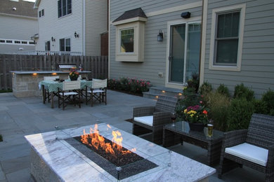 Réalisation d'une terrasse arrière minimaliste de taille moyenne avec un foyer extérieur et des pavés en pierre naturelle.