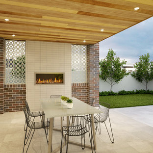 Foto di un patio o portico minimalista di medie dimensioni e dietro casa con un caminetto, pavimentazioni in pietra naturale e un tetto a sbalzo