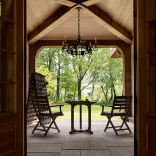 Idee per un grande patio o portico vittoriano dietro casa con pavimentazioni in pietra naturale e un tetto a sbalzo