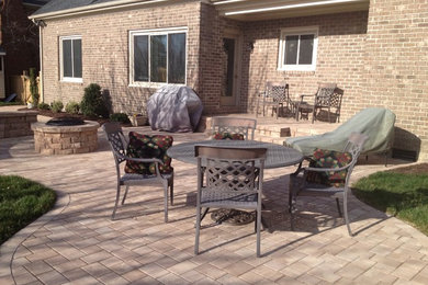 Inspiration for a mid-sized timeless backyard brick patio remodel in Other with a fire pit and no cover