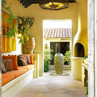 Esempio di un patio o portico mediterraneo in cortile con un tetto a sbalzo, un focolare e pavimentazioni in pietra naturale