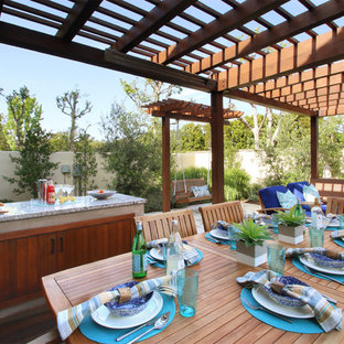 Patio kitchen - mid-sized transitional backyard stone patio kitchen idea in Los Angeles with a pergola