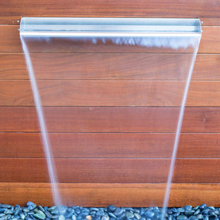 Immagine di un piccolo patio o portico minimal in cortile con fontane, pavimentazioni in cemento e una pergola