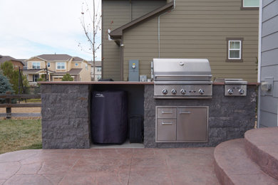 Inspiration for a mid-sized modern backyard stone patio kitchen remodel in Denver with no cover