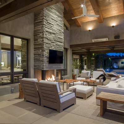Patio - contemporary concrete patio idea in Phoenix with a roof extension and a fireplace
