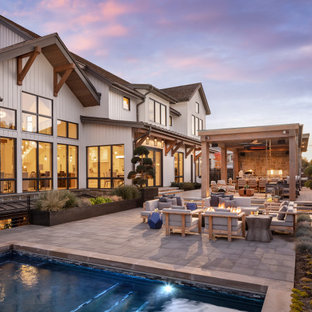 Immagine di un ampio patio o portico country dietro casa con un focolare, pavimentazioni in cemento e una pergola