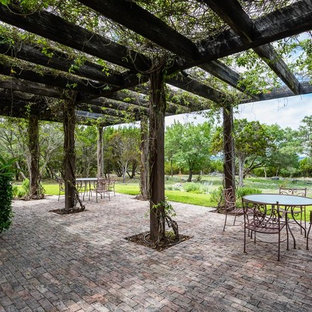 Esempio di un patio o portico country con pavimentazioni in mattoni e una pergola