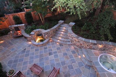 Diseño de patio tradicional renovado grande sin cubierta en patio trasero con fuente y adoquines de piedra natural