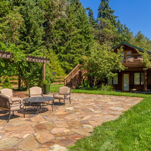 Idee per un ampio patio o portico rustico dietro casa con pavimentazioni in pietra naturale e nessuna copertura