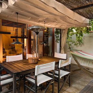 Ispirazione per un piccolo patio o portico tropicale in cortile con piastrelle e un parasole
