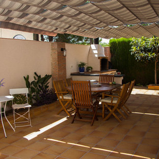 Foto de patio mediterráneo, en patio trasero, con jardín de macetas, suelo de baldosas y toldo