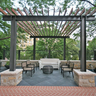 This is an example of a large contemporary courtyard patio in Chicago with natural stone pavers and a pergola.