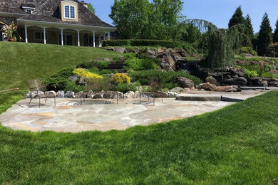 Foto de patio clásico grande sin cubierta en patio trasero con fuente y adoquines de piedra natural