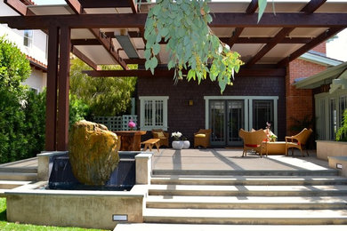 Medium sized world-inspired back patio in Los Angeles with a water feature and a roof extension.