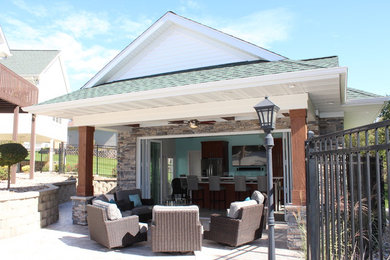 Réalisation d'une grande terrasse arrière craftsman avec une cuisine d'été, des pavés en béton et une extension de toiture.