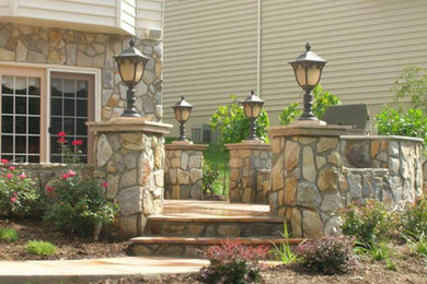Example of a mid-sized stone patio design in DC Metro with no cover