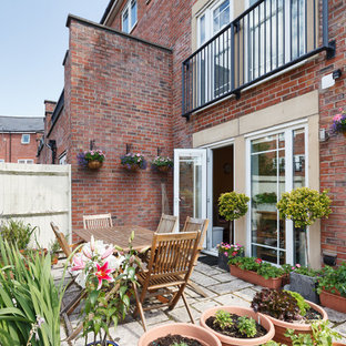 This is an example of a classic back patio in Manchester with a potted garden, concrete paving and no cover.